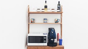 A kitchen counter with a microwave, coffee maker, and storage jars. - Mondello Beach Rooms (Palermo)