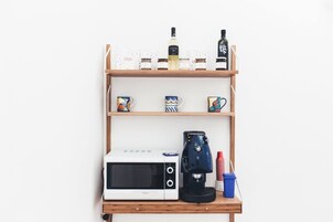 Uma bancada de cozinha com micro-ondas, máquina de café e potes de armazenamento.