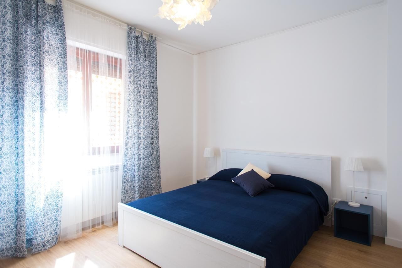 Ein Schlafzimmer mit einem Bett, Nachttischen und einem Fenster mit Vorhängen.
