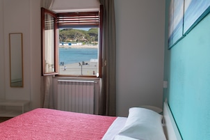 Un dormitorio con cama, ventana y vistas a la playa, además de un radiador.