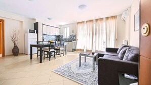 A modern living room with a sofa, a coffee table, and a dining area with chairs and a table. - Magnificent 101m² homm Apartment, 4th (Athens)