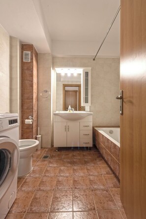Ein Badezimmer mit Waschmaschine, Toilette, Waschbecken und Badewanne.