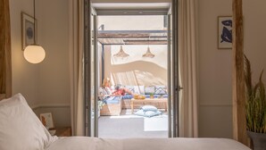 Une chambre avec un lit, un plafond en bois, une fenêtre et une vue sur un espace extérieur aménagé avec des sièges.