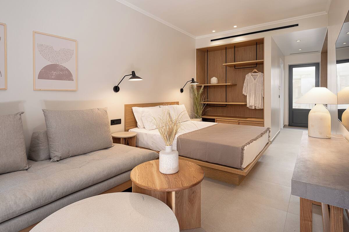 Um quarto moderno com cama, sofá, mesas de cabeceira e guarda-roupa.