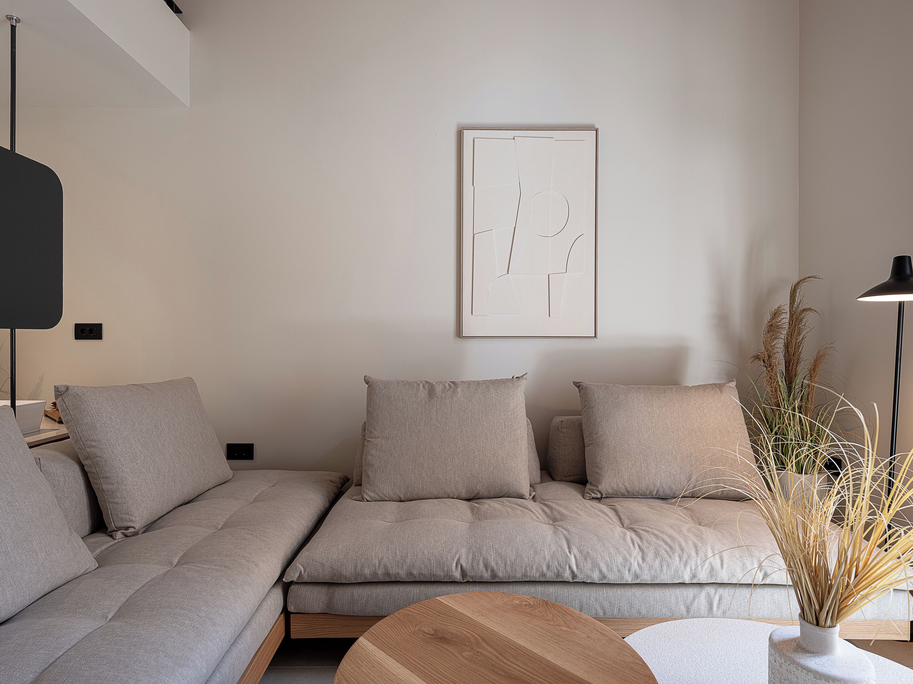 A modern living room with a sofa, a coffee table, and a wall-mounted artwork.