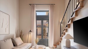 Un salon moderne avec un canapé, une table basse ronde en bois, un téléviseur à écran plat et un escalier avec des marches en bois.