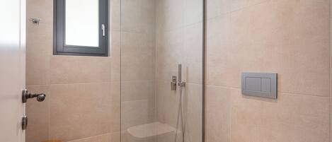 Une salle de bain moderne avec une douche à parois de verre, des toilettes et un petit tabouret en bois.