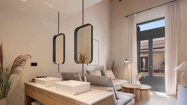 Une salle de bain moderne avec un meuble-lavabo en bois, deux miroirs et une grande fenêtre donnant sur l’extérieur.