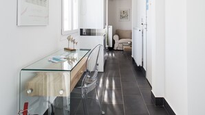A modern hallway with a glass table, white walls, and a kitchen area in the distance. - 37.5m² homm Penthouse in Athens with 43m² Terrace (Athens)