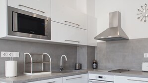 A modern kitchen with white cabinetry, a stainless steel microwave, a gas stove, and a stainless steel range hood. - 37.5m² homm Penthouse in Athens with 43m² Terrace (Athens)