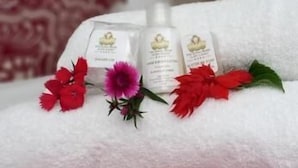 Ein ordentlich gefaltetes weißes Handtuch mit roten und einer rosa Blume auf einem Bett.