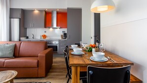 A modern kitchen with grey cabinets, a red backsplash, and a wooden dining table set for four. - Comfortable apartment recently renovated and in the city center (Barcelona)