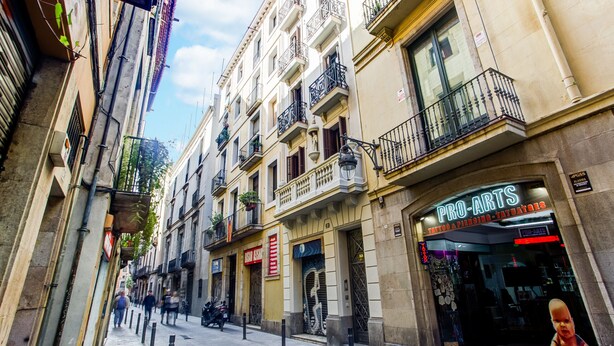 A narrow street lined with multi-story buildings, including a tattoo and piercing shop. - Comfortable apartment recently renovated and in the city center (Barcelona)