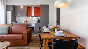 Une cuisine moderne avec des meubles gris, un crédence rouge et une table à manger en bois pour quatre personnes.