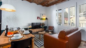 Un salon moderne avec une table à manger en bois mise pour le repas, un canapé et un téléviseur.