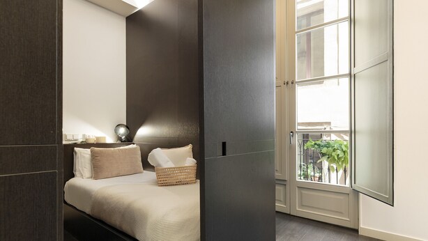 A modern bedroom with a bed, bedside table, and a window with a view of the outside. - Modern and comfortable apartment in the heart of the city (Barcelona)