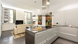 A modern kitchen with a central island, stainless steel appliances, and a large window. - Modern and comfortable apartment in the heart of the city (Barcelona)
