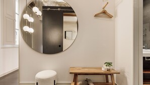 A room with a round mirror, a wooden bench with shoes, a hanging wooden hanger, and a small plant. - Modern and comfortable apartment in the heart of the city (Barcelona)