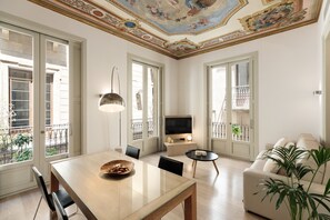A spacious living room with a dining area, large windows, a TV, and a balcony. - Modern and comfortable apartment in the heart of Barcelona (Barcelona)