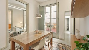 Un comedor moderno con una mesa de madera, sillas blancas y un suelo estampado.