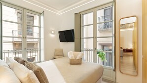 Une chambre à coucher avec un lit, une télévision et une fenêtre donnant sur un balcon.