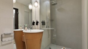 A modern bathroom with two sinks, a glass shower enclosure, and a towel on the floor. - Modern and comfortable studio in the heart of the city (Barcelona)