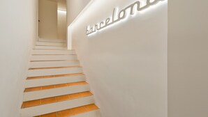 A staircase with white steps and a wall with the word "Barcelona" illuminated. - Cozy and elegant studio in the city center (Barcelona)