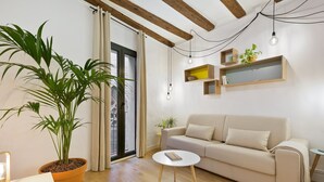 A modern living room with a sofa, a round coffee table, and a potted plant. - Cozy and elegant studio in the city center (Barcelona)