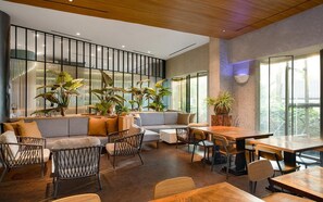 A modern interior with a seating area, tables, and large windows. - Oakwood Suites Kuningan Jakarta (Jakarta)
