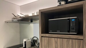 A modern kitchen with a built-in microwave, a coffee maker, and a stainless steel sink. - Oakwood Suites Kuningan Jakarta (Jakarta)