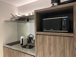 Una cocina moderna con microondas integrado, cafetera y pileta de acero inoxidable.