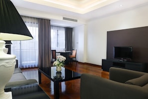 Una sala de estar moderna con un sofá, una mesa de centro con un jarrón, un televisor de pantalla plana y un comedor con sillas y una mesa.
