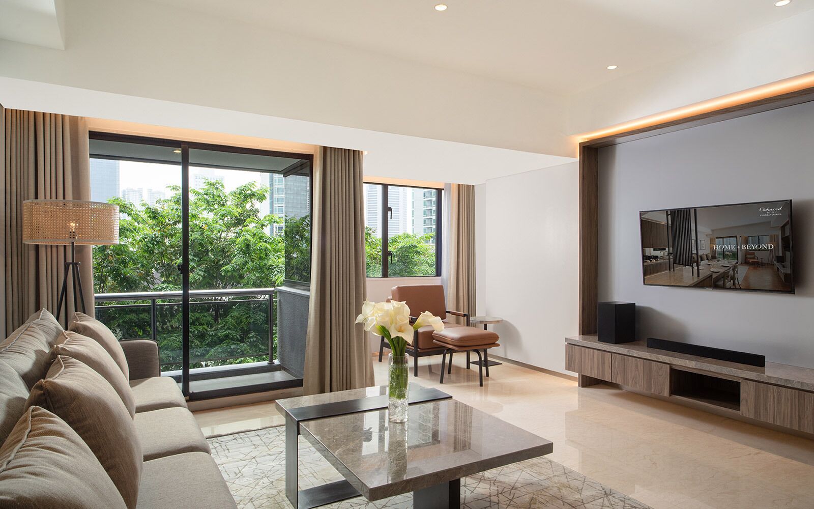 Un salon moderne avec un canapé, une table basse et un téléviseur à écran plat fixé au mur.