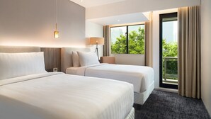 A hotel room with two beds, a large window with a view of greenery, and a balcony. - Oakwood Suites Kuningan Jakarta (Jakarta)