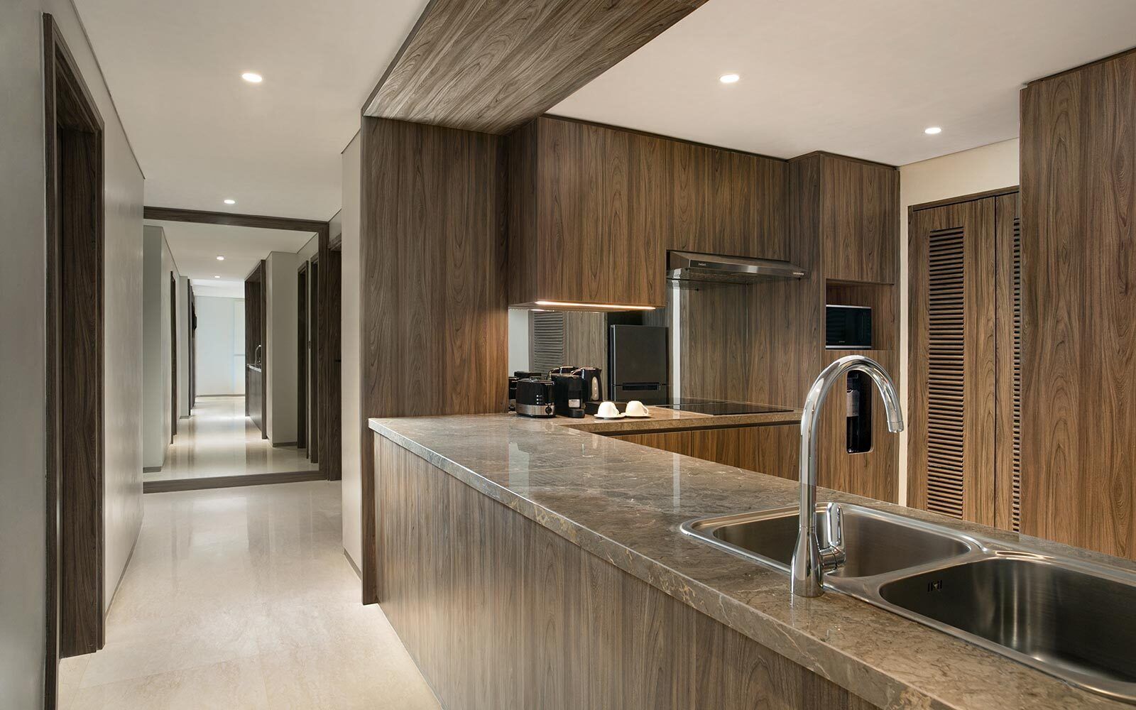 Une cuisine moderne dotée d’un îlot central, d’éviers en acier inoxydable et de meubles de rangement en bois.