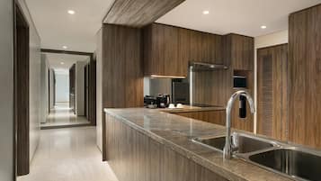 Une cuisine moderne dotée d’un îlot central, d’éviers en acier inoxydable et de meubles de rangement en bois.