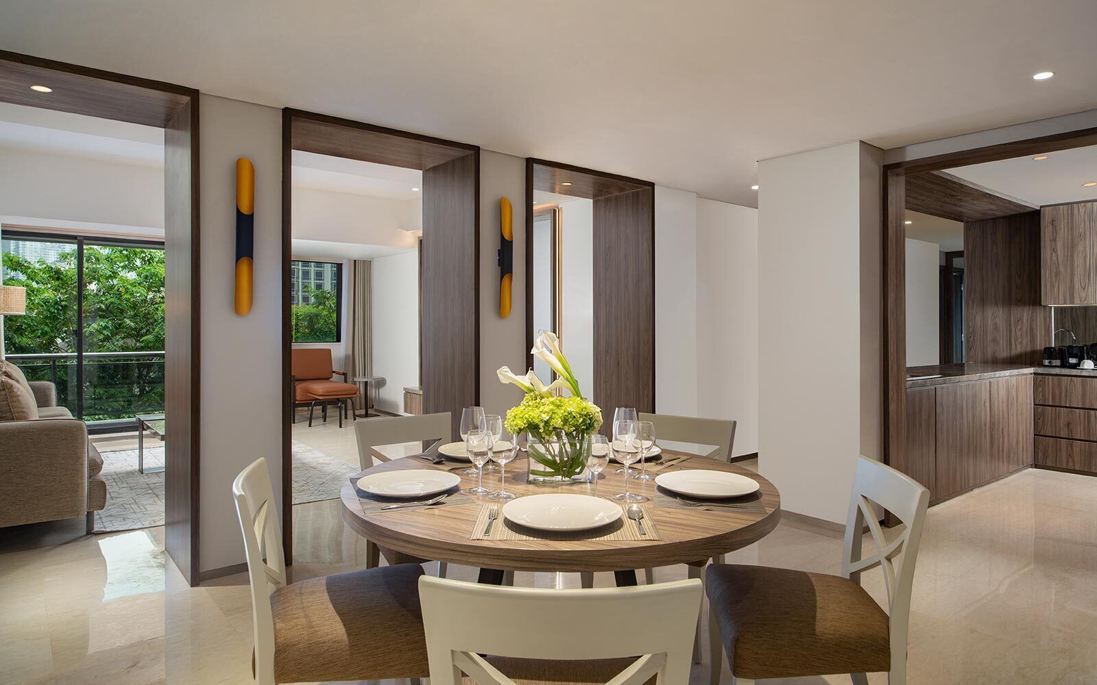 A modern dining area with a round table, white chairs, and a vase of flowers.