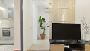 Ein modernes Wohnzimmer mit Fernseher, Blumentopf und Wandpaneele aus Holz.