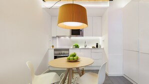 A compact kitchen with white cabinetry, a built-in microwave, and a round wooden table with chairs.