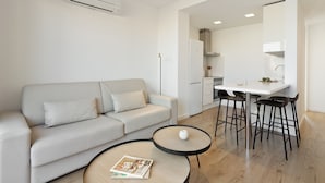 Un salon moderne comprenant un canapé, une table basse et un coin cuisine avec une table à manger et des chaises.
