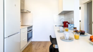 Une cuisine moderne avec des meubles blancs, une hotte en acier inoxydable et un plancher en bois.