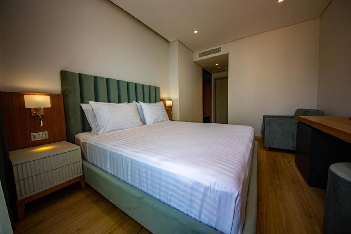 Ein modernes Hotelzimmer mit einem großen Bett, Nachttischen mit Lampen, einem Schreibtisch und einem Sessel.