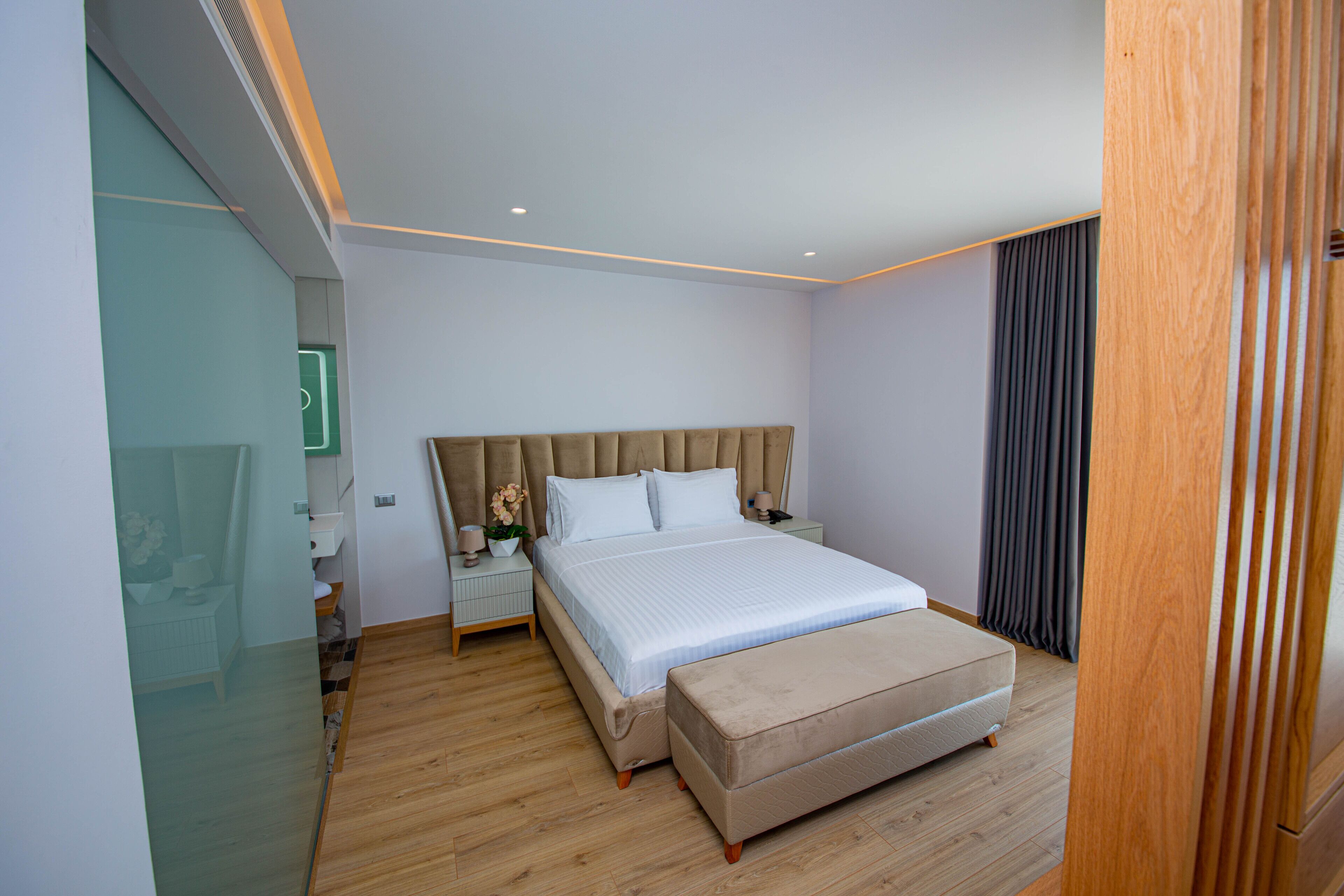 Ein modernes Schlafzimmer mit einem großen Bett, Nachttischen, einem kleinen Tisch und einem Holzboden.
