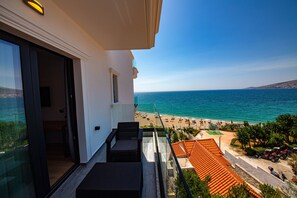 Uma varanda com vista para o mar, a praia e um estacionamento.