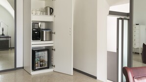 Una cocina compacta con refrigerador, microondas y cafetera.