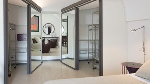 Habitación de hotel moderna con una cama grande, un escritorio, una silla, un armario y un baño con ducha e inodoro.