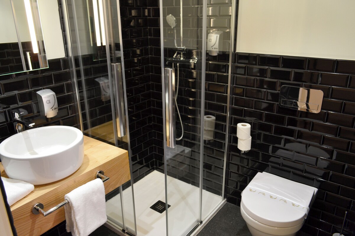 Une salle de bain moderne avec une douche à parois de verre, un lavabo blanc et des toilettes.
