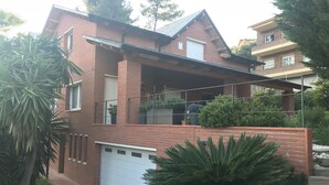 A two-story house with a garage, a balcony, and a covered patio area. - Beautiful apartment, garden and swimming pool, 20km from Barcelona, suitable for pets (Vallirana)