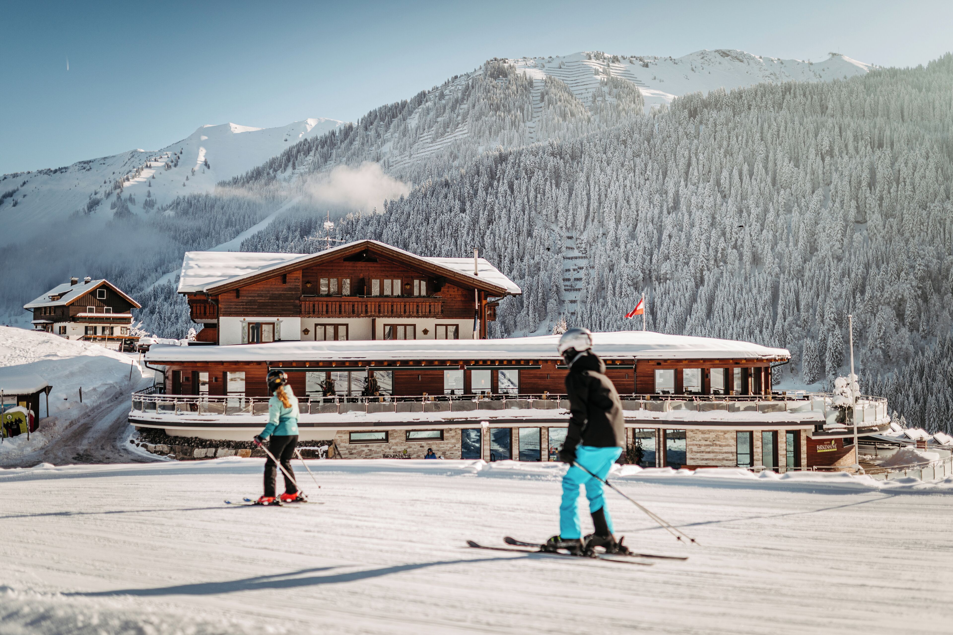 A wooden lodge with a ski slope in the background.