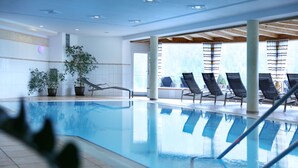 An indoor swimming pool with lounge chairs and potted plants. - Hotel Birkenhöhe (Mittelberg)